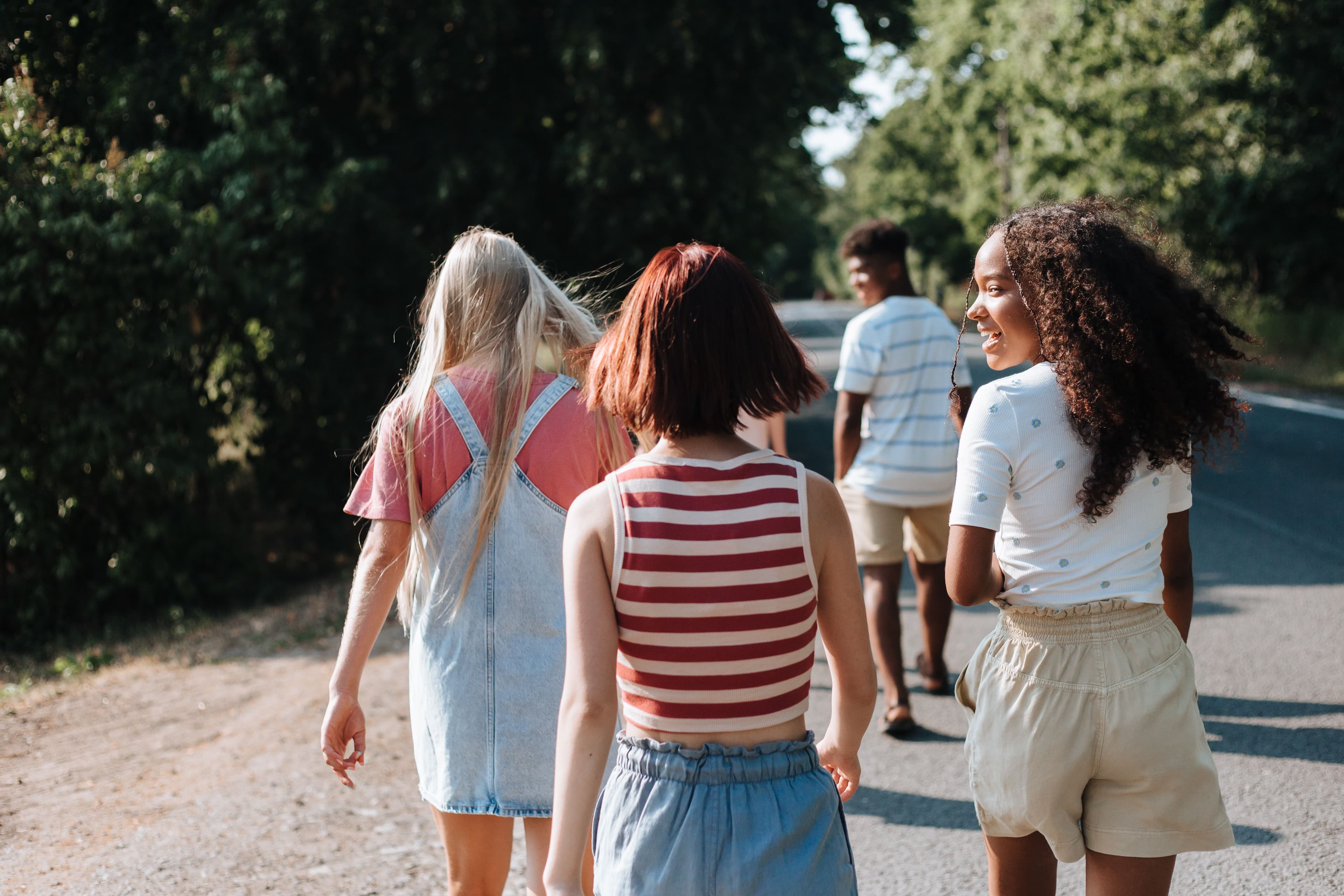 Young people walking together on a tree-lined road